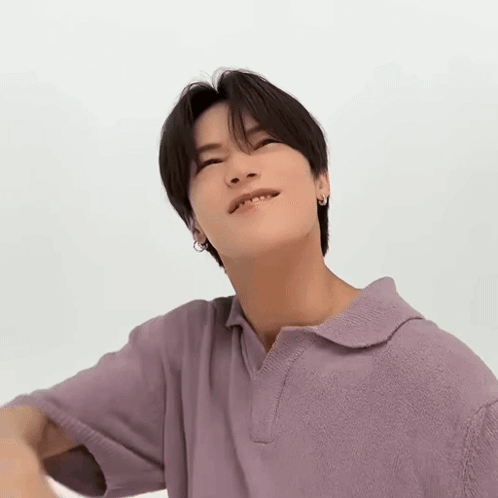 A Young Man Is Wearing A Purple Polo Shirt And Looking Up At The Camera . GIF