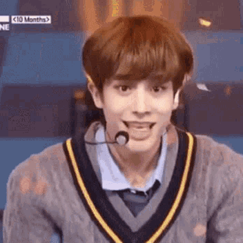 A Young Man Is Wearing A Sweater And A Microphone . GIF