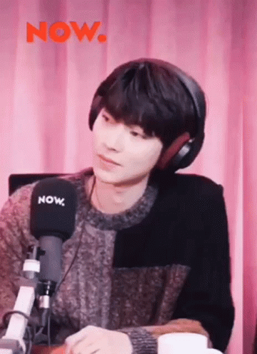 A Young Man Is Wearing Headphones And Sitting In Front Of A Microphone . GIF