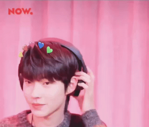 A Young Man Is Wearing Headphones With Hearts On His Head . GIF