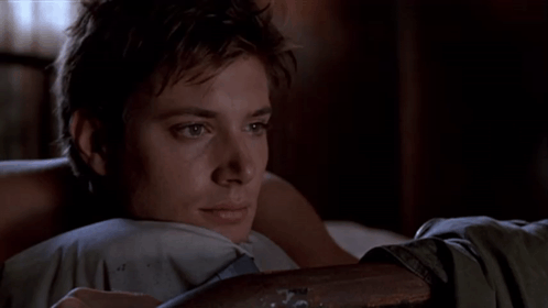A Young Man Laying On A Bed With His Head Resting On A Pillow GIF