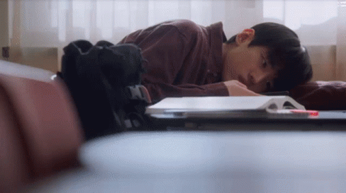 A Young Man Laying On A Couch With His Head On A Book . GIF