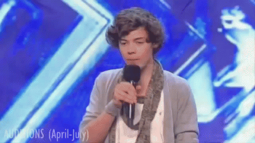 A Young Man Singing Into A Microphone On A Stage With The Words Auditions ( April July ) Written On The Bottom GIF