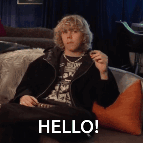 A Young Man Sitting On A Couch With The Word Hello Written On The Bottom GIF