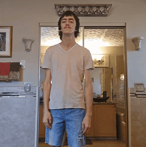 A Young Man Standing In Front Of A Sliding Glass Door In A Kitchen GIF