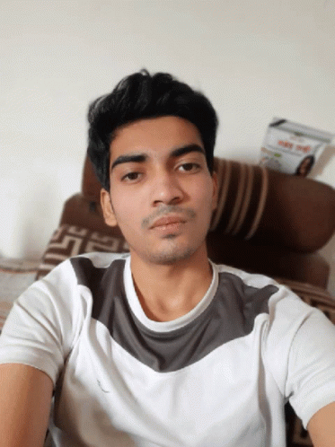 A Young Man Taking A Selfie In Front Of A Couch With A Magazine On It That Says ' Day ' On It GIF