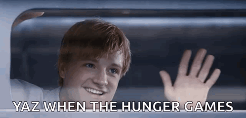 A Young Man Waving Out Of A Window With Yaz When The Hunger Games Below Him GIF