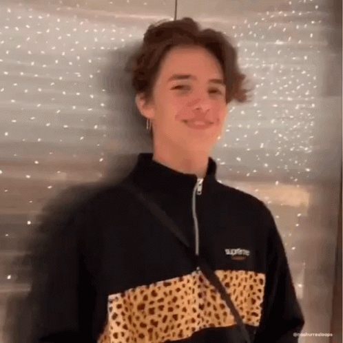 A Young Man Wearing A Black And Leopard Print Supreme Jacket Is Smiling . GIF