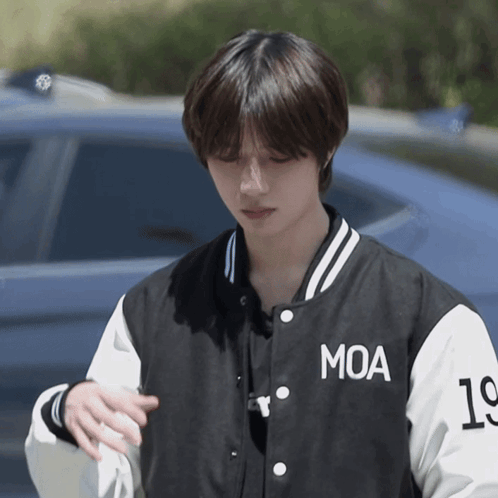A Young Man Wearing A Black And White Moa Baseball Jacket GIF