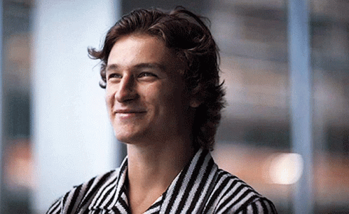 A Young Man Wearing A Black And White Striped Shirt Is Smiling GIF