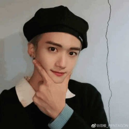 A Young Man Wearing A Black Beret Is Making A Funny Face With His Hand On His Chin . GIF