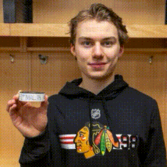 A Young Man Wearing A Black Chicago Blackhawks Hoodie Is Holding A Piece Of Paper GIF