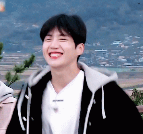 A Young Man Wearing A Black Hoodie And A White Shirt Smiles GIF