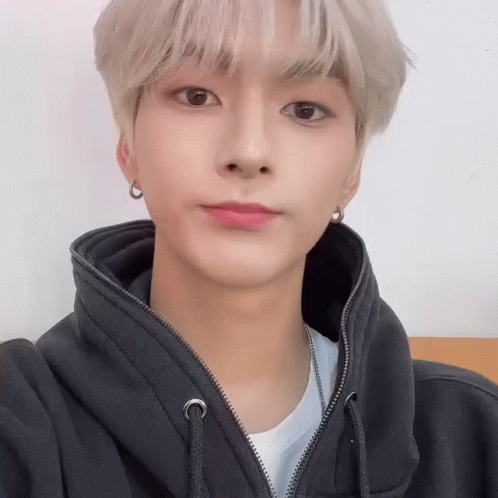 A Young Man Wearing A Black Hoodie And Earrings Is Looking At The Camera . GIF