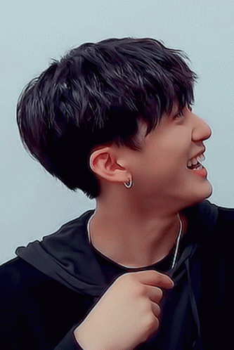 A Young Man Wearing A Black Hoodie And Earrings Smiles GIF