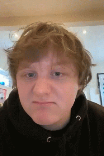 A Young Man Wearing A Black Hoodie With The Letter C On The Front Of It GIF