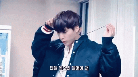 A Young Man Wearing A Black Jacket And A White Shirt Is Holding A String Around His Neck . GIF