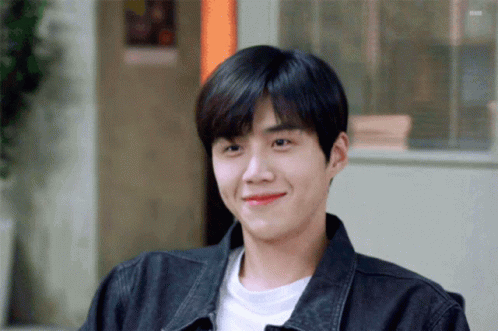 A Young Man Wearing A Black Jacket And A White Shirt Smiles For The Camera GIF
