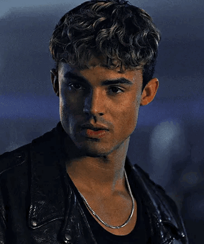 A Young Man Wearing A Black Leather Jacket And A Chain Around His Neck . GIF