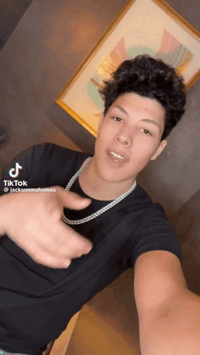 A Young Man Wearing A Black Shirt And A Necklace Is Taking A Selfie With A Tiktok Hashtag GIF