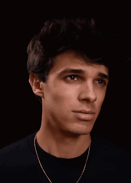 A Young Man Wearing A Black Shirt And Gold Chain Is Smiling GIF
