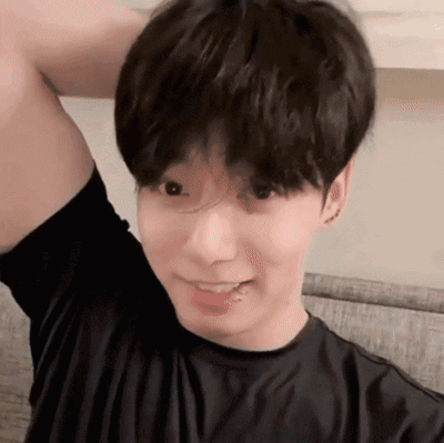 A Young Man Wearing A Black Shirt Is Smiling With His Arm Up GIF