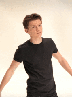 A Young Man Wearing A Black T-Shirt Is Standing With His Arms Outstretched . GIF