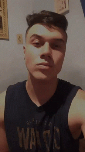 A Young Man Wearing A Black Tank Top That Says Waldo GIF