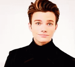 A Young Man Wearing A Black Turtleneck And A Black Jacket Is Making A Funny Face . GIF