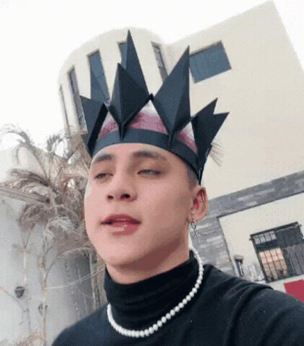 A Young Man Wearing A Black Turtleneck And A Pearl Necklace GIF