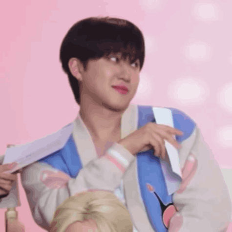 A Young Man Wearing A Blue And White Jacket Is Holding A Piece Of Paper . GIF