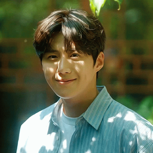 A Young Man Wearing A Blue And White Striped Shirt Is Smiling GIF