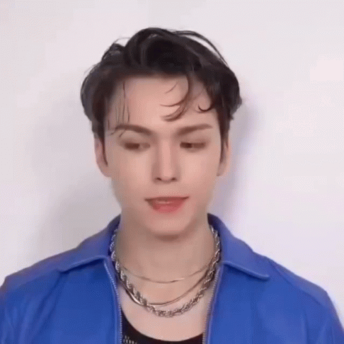 A Young Man Wearing A Blue Jacket And A Necklace Is Making A Funny Face . GIF