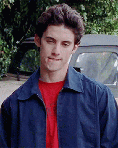 A Young Man Wearing A Blue Jacket And A Red T-Shirt Is Standing In Front Of A Truck GIF
