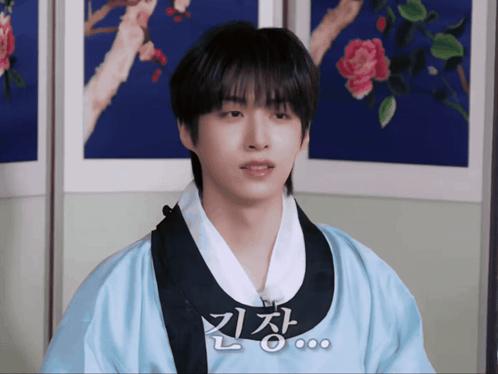 A Young Man Wearing A Blue Kimono With Chinese Writing On The Front GIF