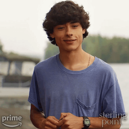 a young man wearing a blue shirt and a watch is standing in front of a sign that says sterling point