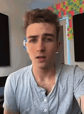 A Young Man Wearing A Blue Shirt Is Looking At The Camera . GIF
