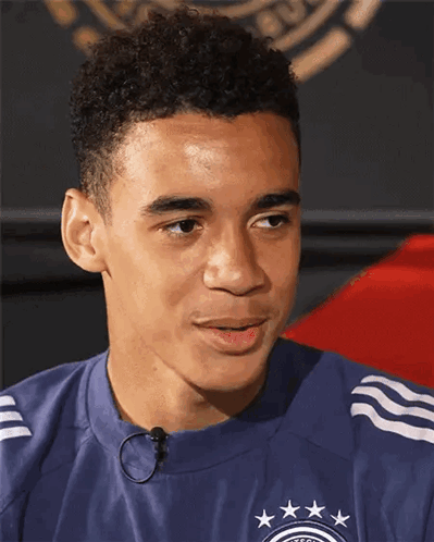 A Young Man Wearing A Blue Shirt With Stars On It Looks To The Side GIF