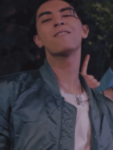 A Young Man Wearing A Bomber Jacket And A White Shirt Is Giving A Thumbs Up GIF