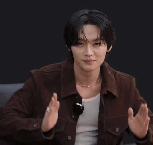 A Young Man Wearing A Brown Jacket And A Necklace Is Clapping GIF