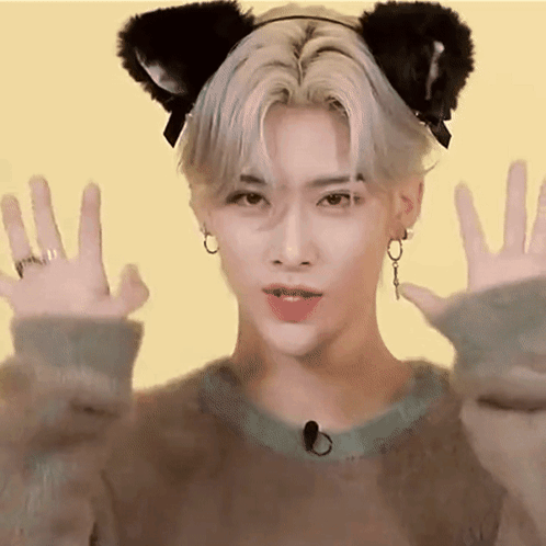 A Young Man Wearing A Cat Ear Headband Is Making A Cat Face With His Hands . GIF