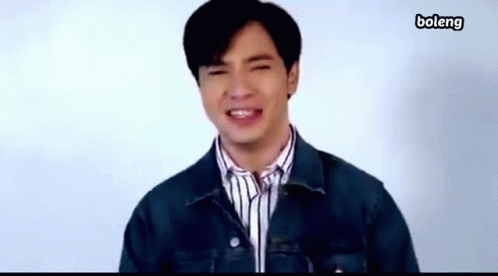 A Young Man Wearing A Denim Jacket And Striped Shirt Is Smiling . GIF