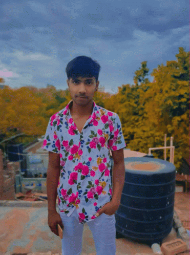 A Young Man Wearing A Floral Shirt Is Standing On A Roof GIF