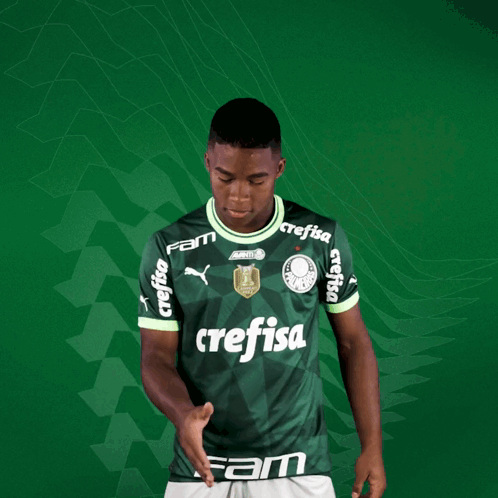 a young man wearing a green crefisa jersey holds out his hand