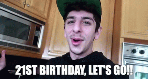 A Young Man Wearing A Green Hat Is Standing In Front Of A Microwave In A Kitchen . GIF