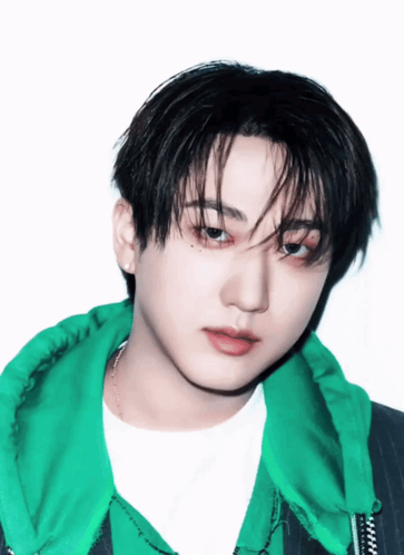 A Young Man Wearing A Green Jacket And A White Shirt Looks At The Camera GIF