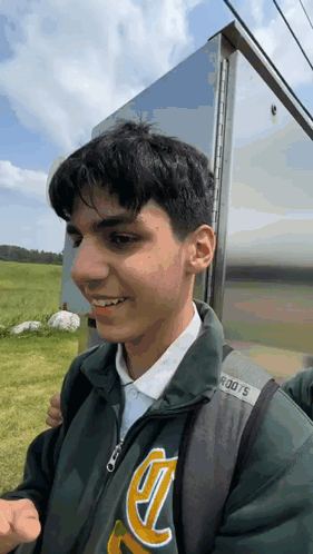 A Young Man Wearing A Green Jacket With The Letter T On It GIF