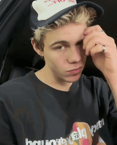 A Young Man Wearing A Hat And A Black Shirt That Says " Lucky " On It GIF