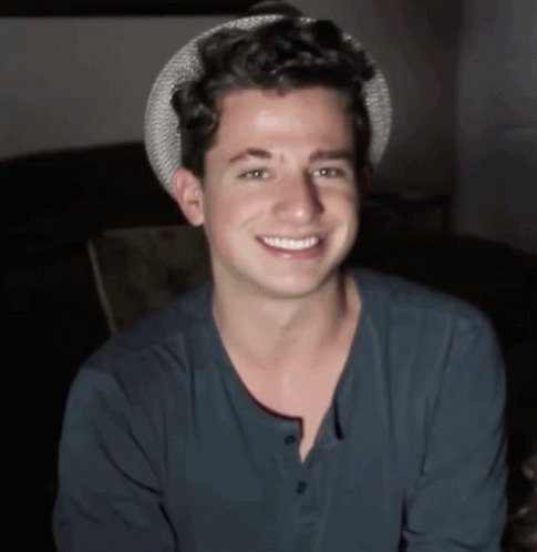 A Young Man Wearing A Hat And A Blue Shirt Is Smiling GIF