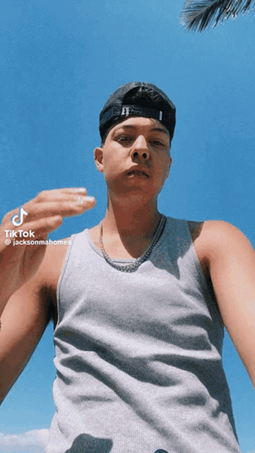 A Young Man Wearing A Hat And A Tank Top Is Taking A Selfie With Tik Tok GIF